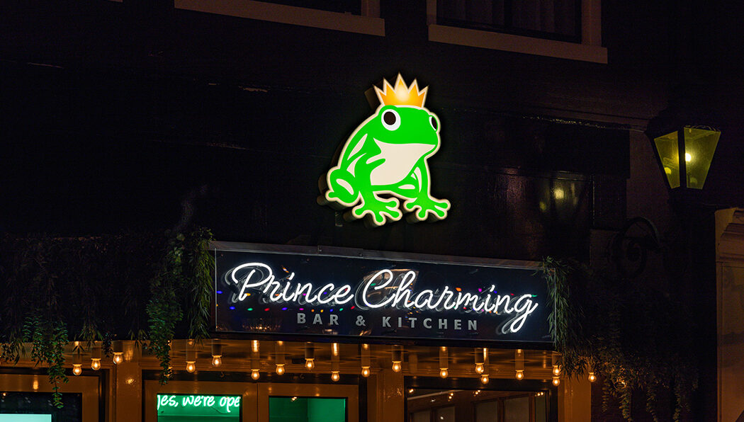 Verlicht logo van een groene kikker en neon tekst Prince Charming Prins Hendrik hotel Amsterdam